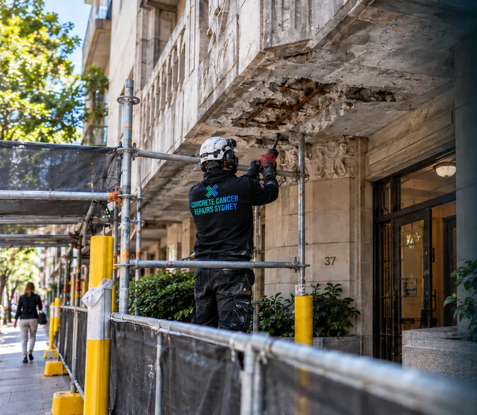 Concrete repair technician working from scaffold outside an occupied heritage building