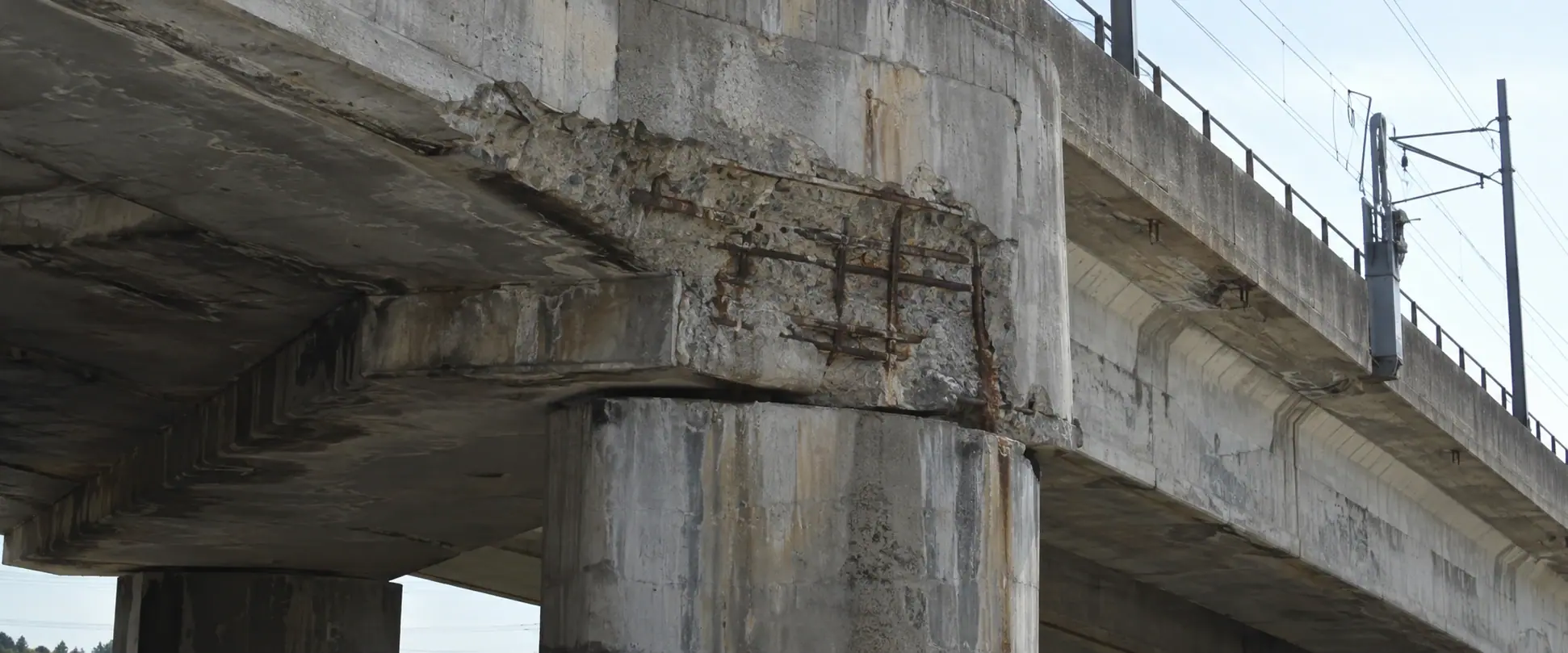 Illustrative BEFORE concept: corrosion-related spalling and cover loss where an elevated rail-bridge beam bears onto a support pier.